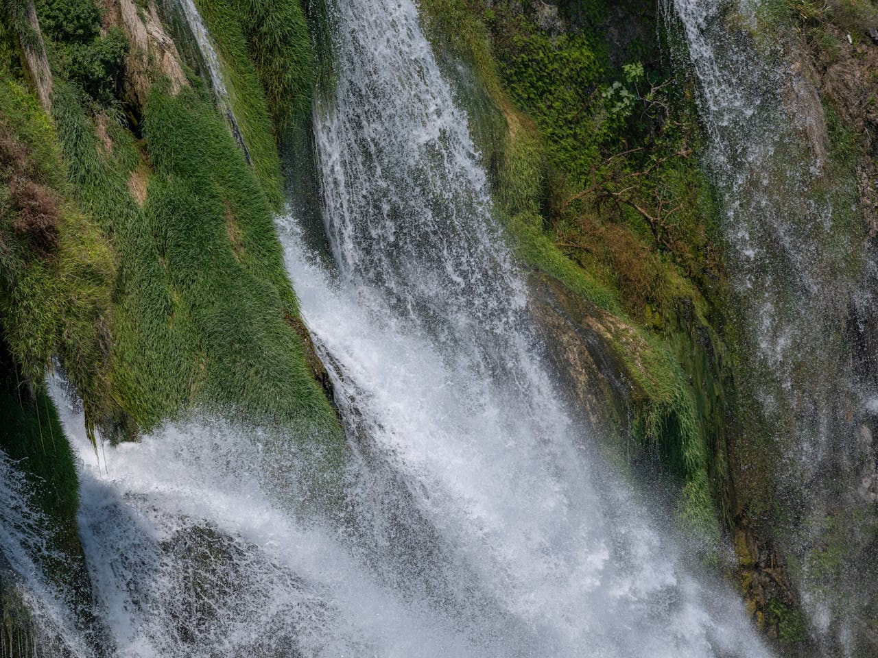 Captivating waterfall cascading over lush green cliffs, showcasing natures beauty and power.